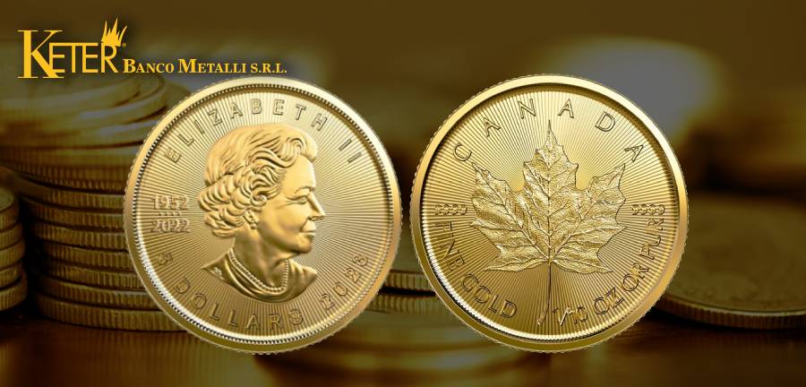 Moneta Maple Leaf d'oro Fior di Conio del 2023 esposta in primo piano con sfondo sfocato di altre monete d'oro. Sulla moneta è raffigurata l'effigie della Regina Elisabetta II sul fronte e una foglia d'acero dettagliata sul retro, con incisioni che indicano il paese di origine, Canada, e il valore di purezza dell'oro. Il logo di Keter Banco Metalli S.r.l. è visibile in alto.
