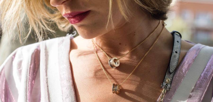 Primo piano di una donna che indossa collane di lusso a strati, con eleganti pendenti in oro, che rappresentano le ultime tendenze dei gioielli per il 2024.