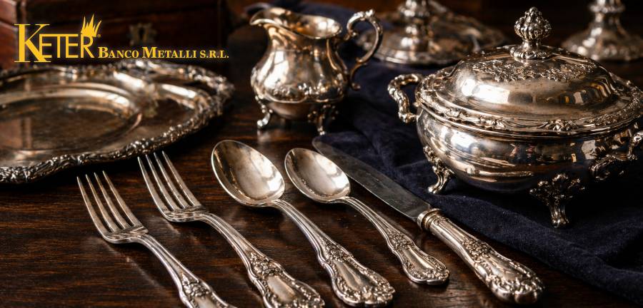 Posate e oggetti in argento antico su tavolo in legno con vassoio e zuppiera in argento lavorato, esempio di argenteria valutata non solo per il peso ma anche per marca, epoca, lavorazione e stato di conservazione